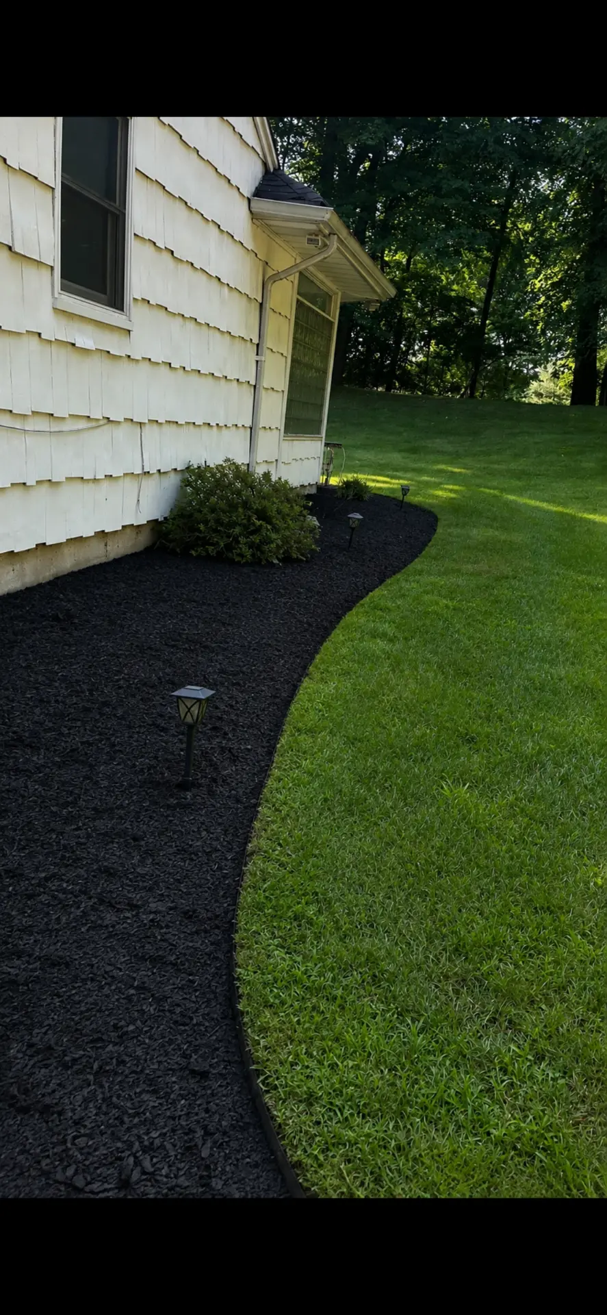 Fresh black mulch, crisp edging and a healthy lawn beside a Rockland County home